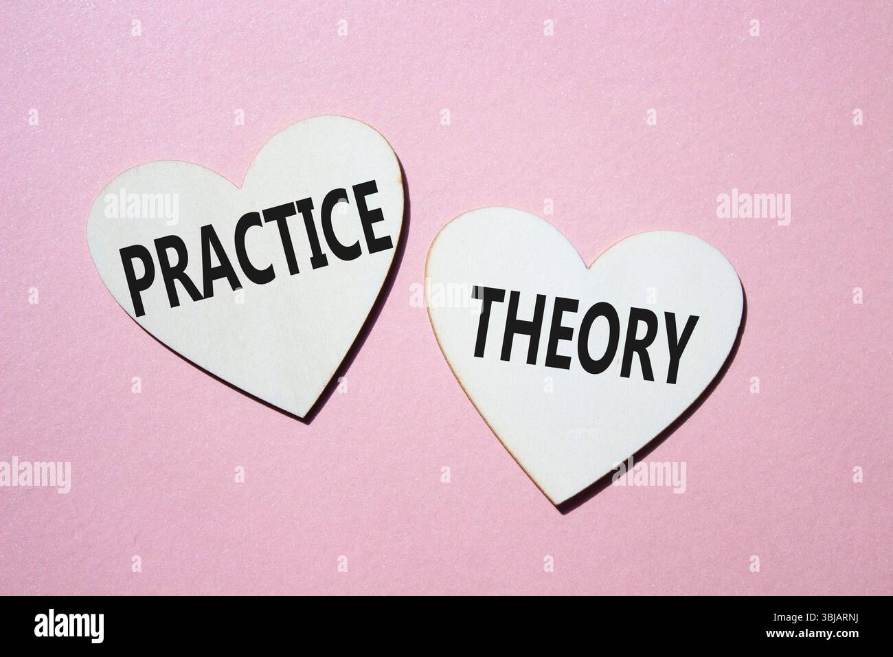 Theorie- oder Praxissymbol. Konzeptwort Theorie oder Praxis auf hölzernen Herzen. Schöner rosafarbener Hintergrund. Business and Theory oder Practice Concept. Kopieren Stockfoto
