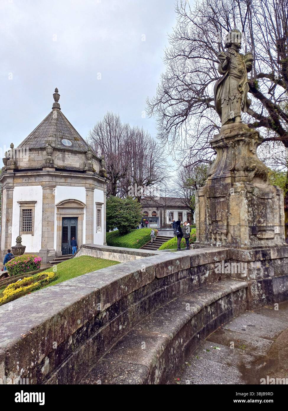Braga Portugal 29. März 2024 Blick auf eine achteckige Kapelle und eine barocke Statue inmitten landschaftlich angelegter Gärten im Bom Jesus Heiligtum-Komplex Stockfoto