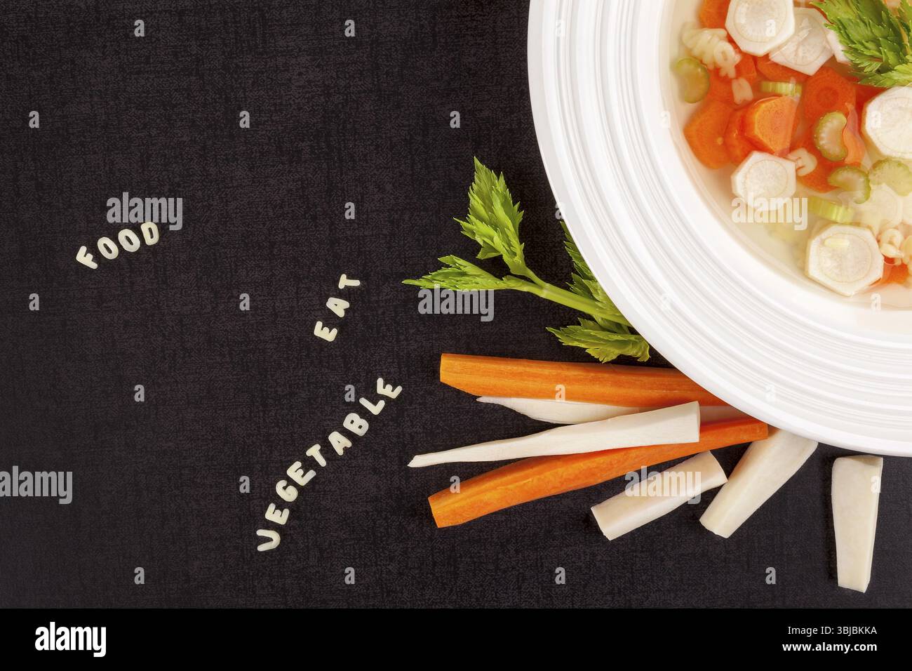 Frische Brühe mit Gemüse und Alphabet-Nudeln auf dunkler Oberfläche von oben. Bouillon mit Worten aus Nudeln. Gastronomie. Hintergrund des Mittagsmenüs Stockfoto