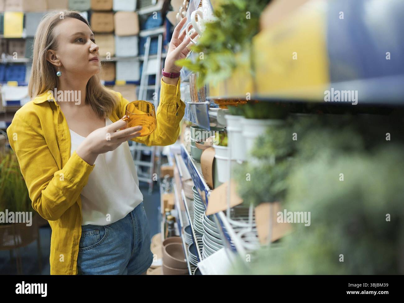 Die Frau wählt Geschirr in einem Laden aus Stockfoto