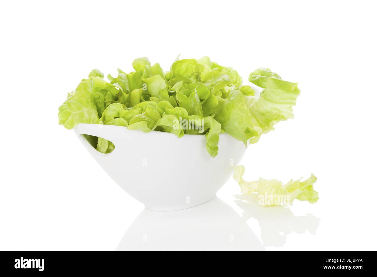 Frischer grüner Salat in weißer Schüssel isoliert auf weißem Hintergrund. Frische gesunde Sommeressen. Kulinarische Kunst. Moderne minimale Bildsprache Stockfoto
