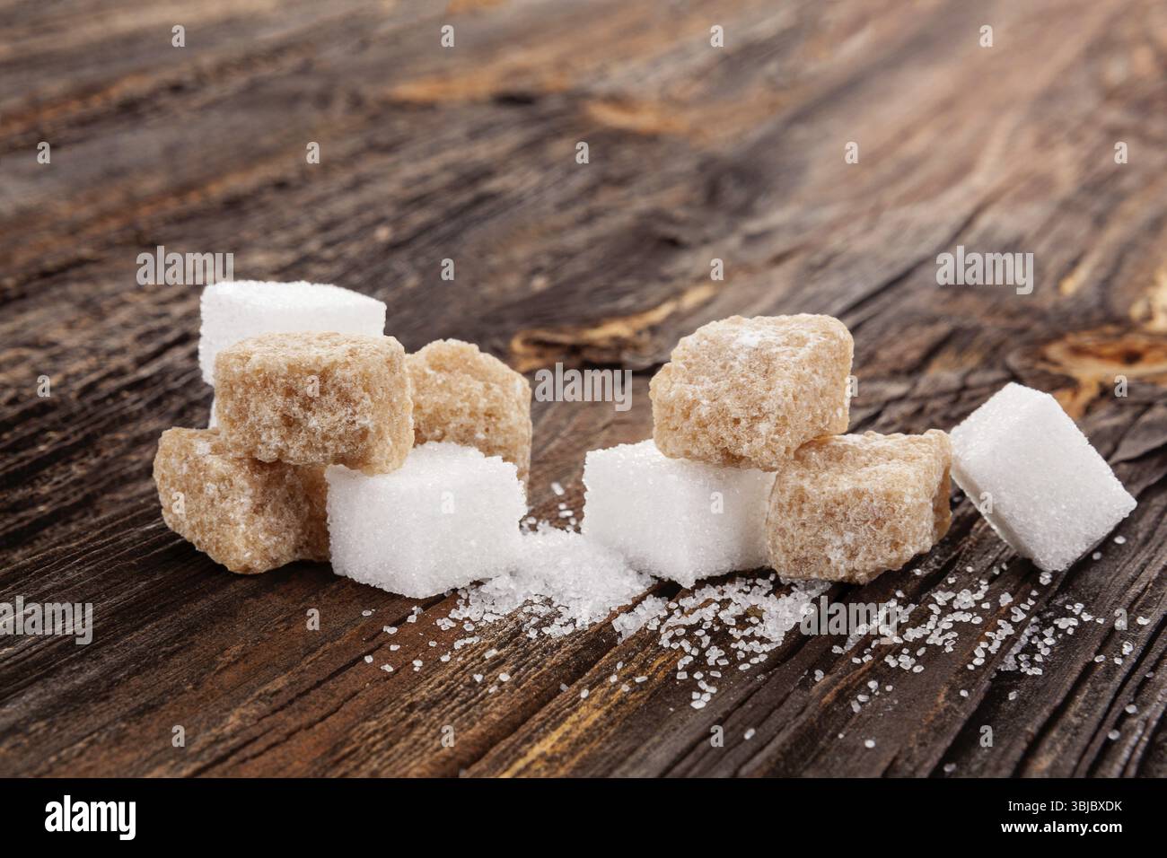 Braune und weiße Kristallzuckerwürfel auf Holztisch Stockfoto
