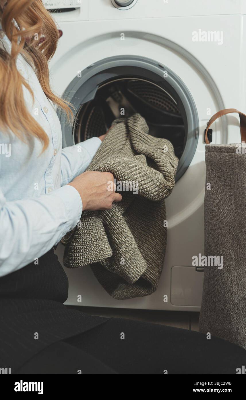 Frau, die Kleidung in die Waschmaschine lädt Stockfoto