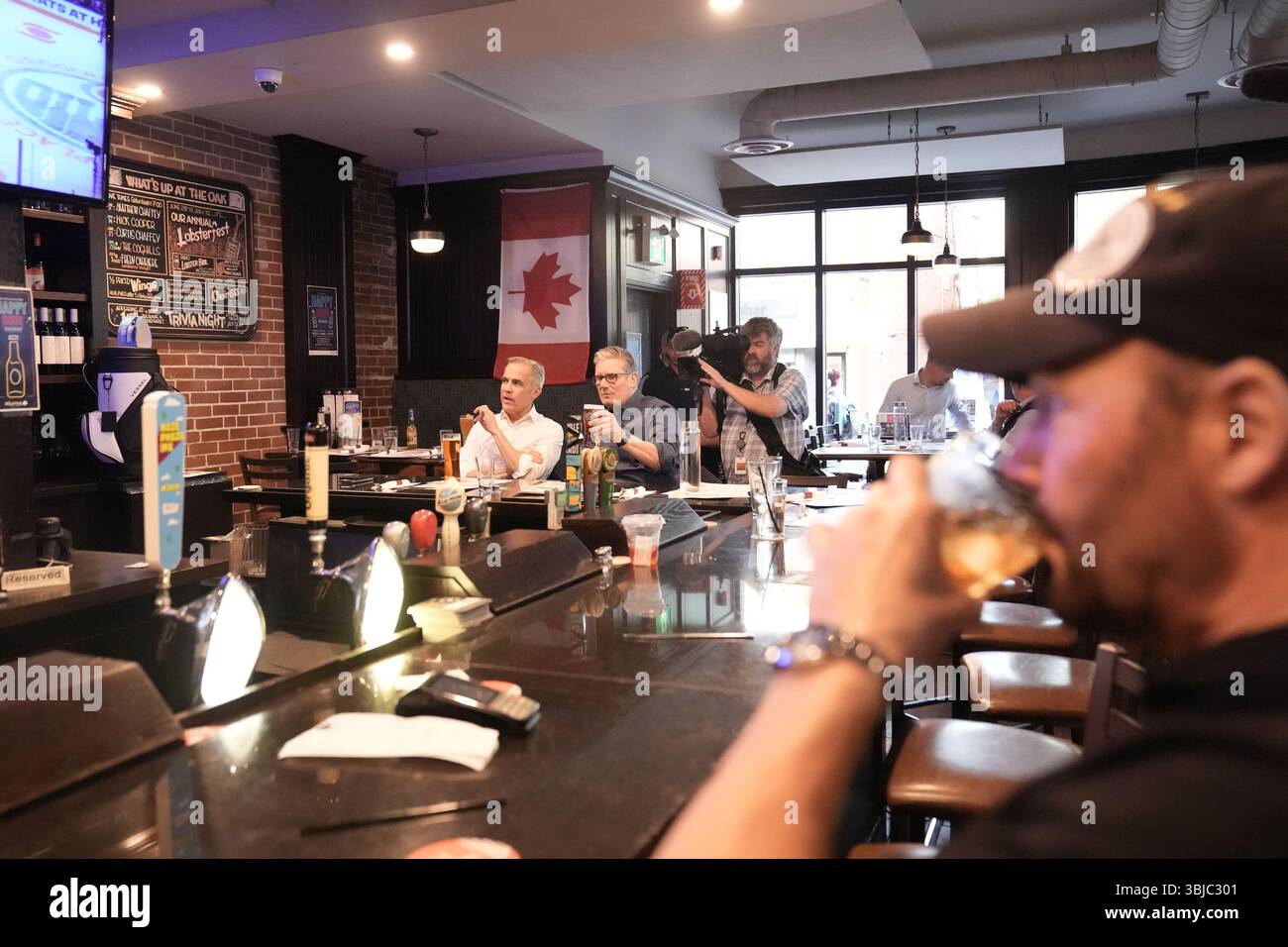 Premierminister Sir Keir Starmer und Premierminister von Kanada Mark Carney trinken Bier, während sie ein Eishockeyspiel im Fernsehen zwischen Edmonton Oilers und Florida Panthers im Royal Oak Pub in Ottawa, Kanada, im Vorfeld des Gipfels der Staats- und Regierungschefs der G7 anschauen. Bilddatum: Samstag, 14. Juni 2025. Stockfoto