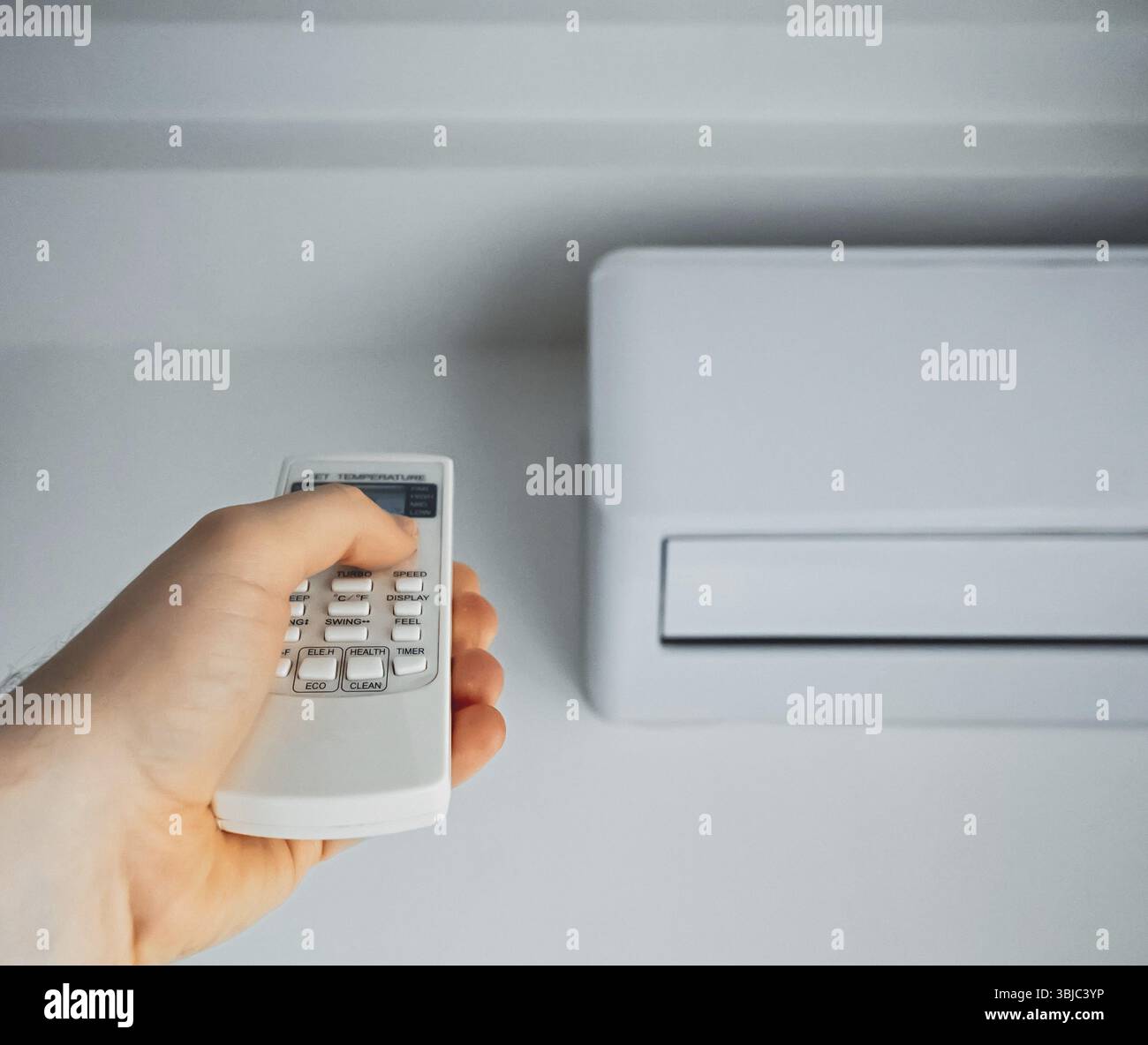 Fernbedienung mit Handgriff, die auf die Klimaanlage gerichtet ist Stockfoto