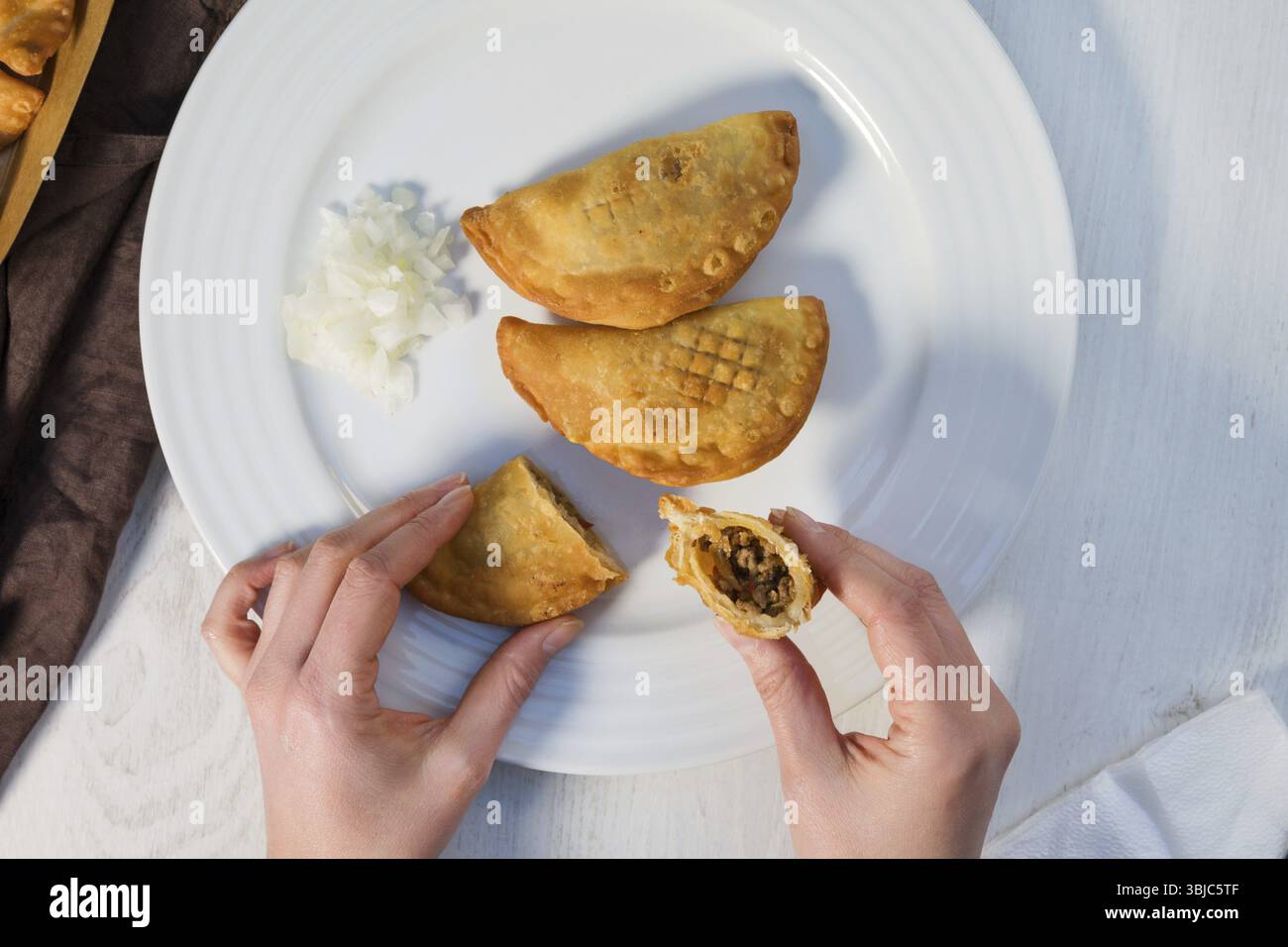 Traditionelles, gebackenes argentinisches Empanadas herzhaftes Gebäck mit Fleisch-Rindfleisch-Füllung mit frischer Zwiebeln auf weißem Teller von oben Stockfoto