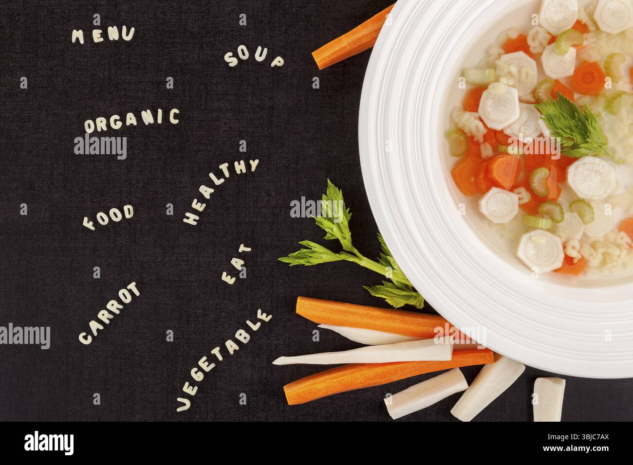 Pasta- und Gemüsesuppe mit Alphabet und Nudelbuchstaben von oben. Dunkle Oberfläche. Gastronomie Hintergrund. Gemüsebrühe Stockfoto