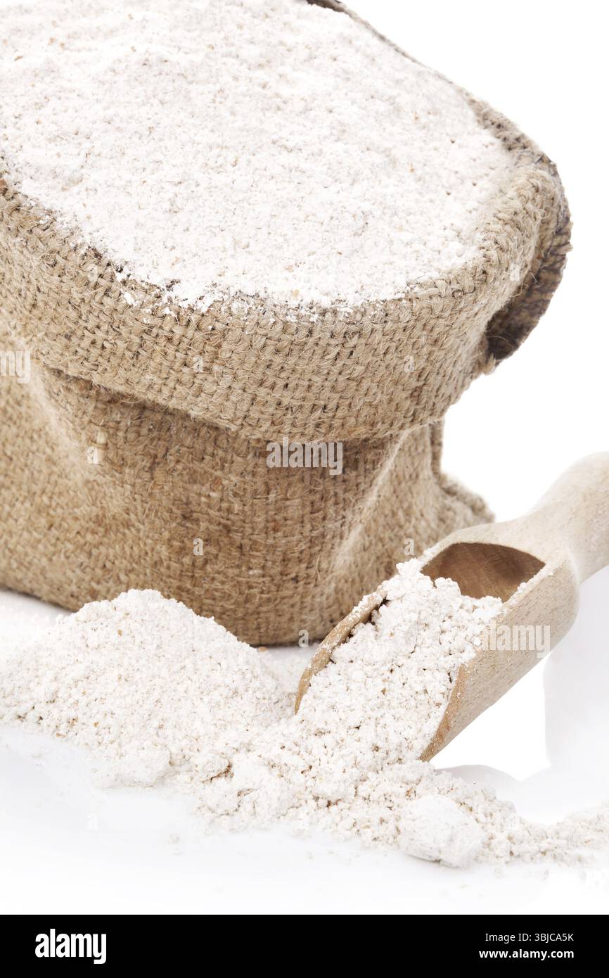 Mehl in braunem Sack und auf Holzlöffel isoliert auf weißem Hintergrund Stockfoto