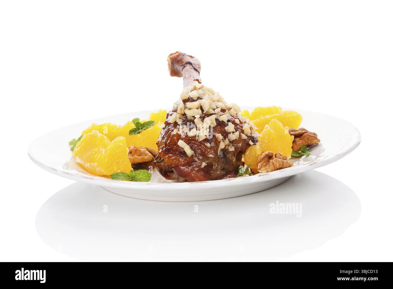 Kulinarische gebratene Ente mit Orangen und Nüssen auf Teller isoliert auf weißem Hintergrund. Köstliches festliches Essen Stockfoto