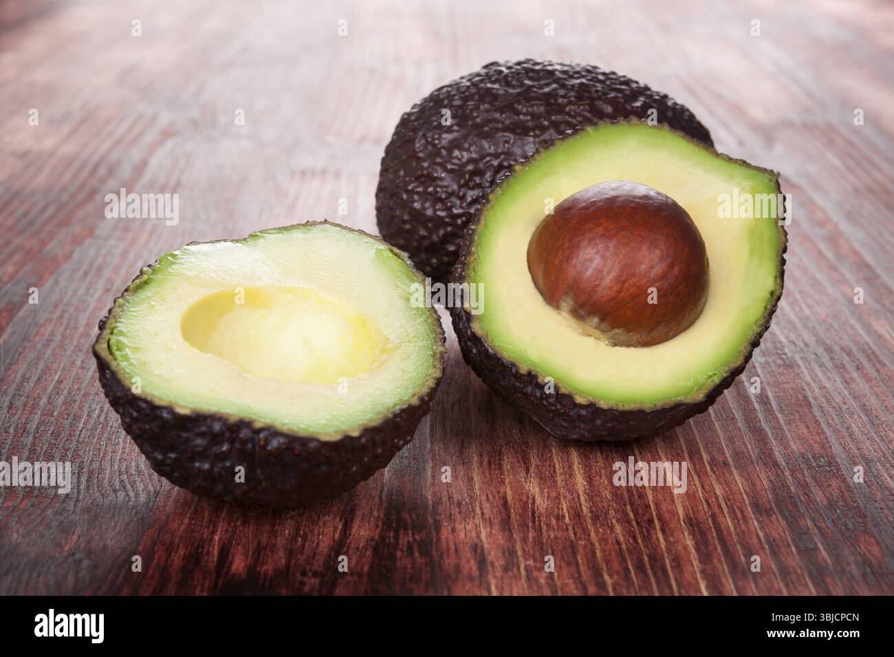 Reife Avocado auf hölzernem Hintergrund. Kulinarische gesunde Fruchternährung Stockfoto