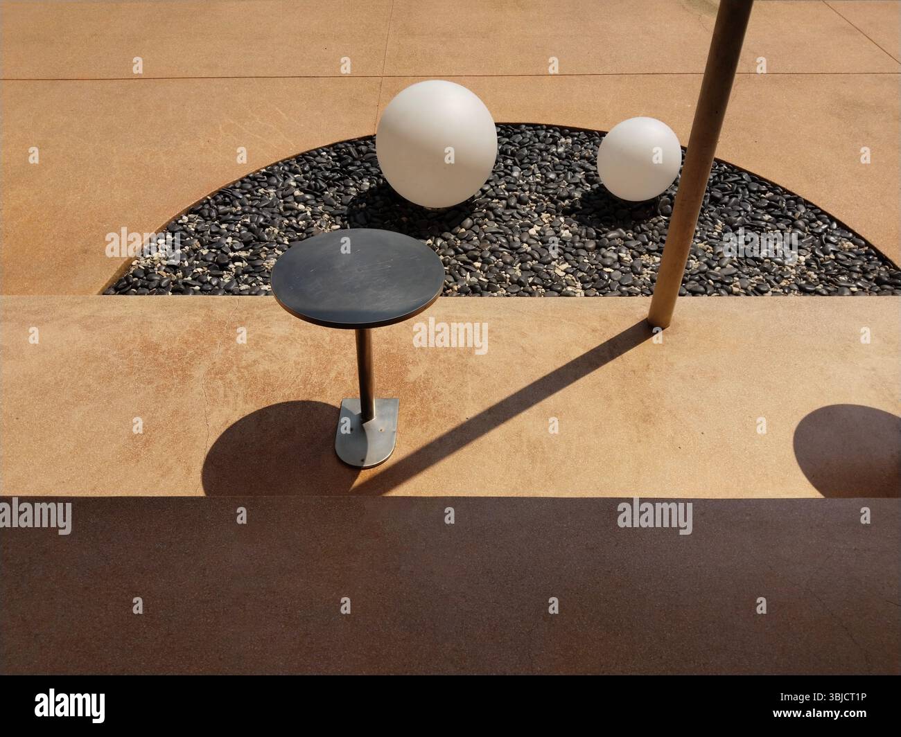 Der einzigartige Außenbereich bietet einfache Möbel, abgerundete Skulpturen und interessante Schatten an einem sonnigen Tag. Stockfoto