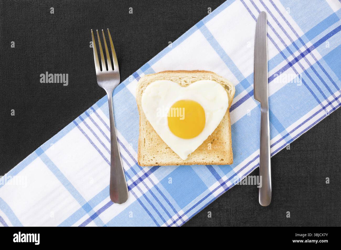 Sonniges Ei in Herzform auf Toast, Blick von oben. Ich liebe das Frühstück. Frische, moderne Bildsprache. Kulinarische Kunst Stockfoto