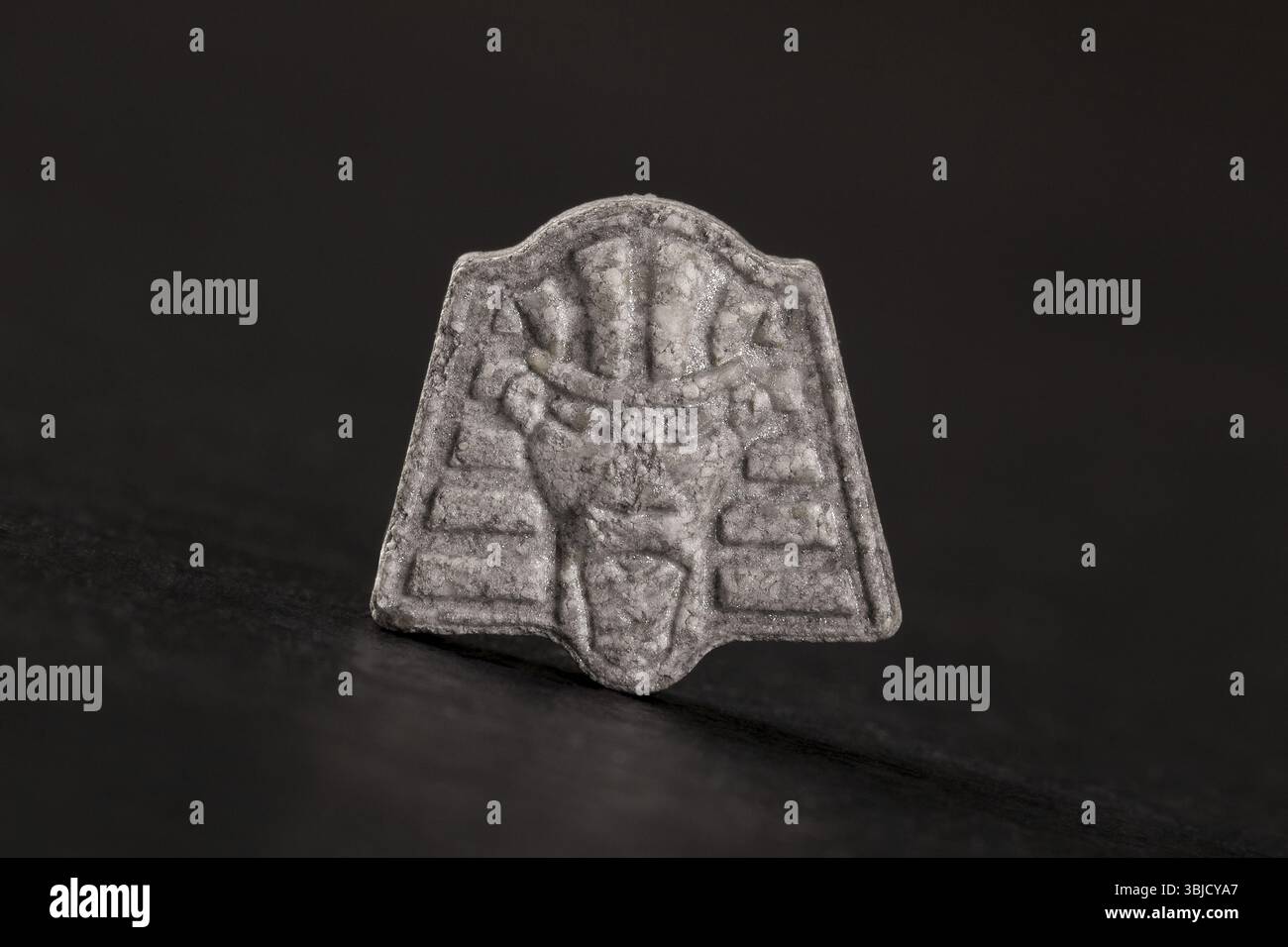 Pharao Ecstasy-Pille auf schwarzem Hintergrund. MDMA-gestützte Psychotherapie Stockfoto