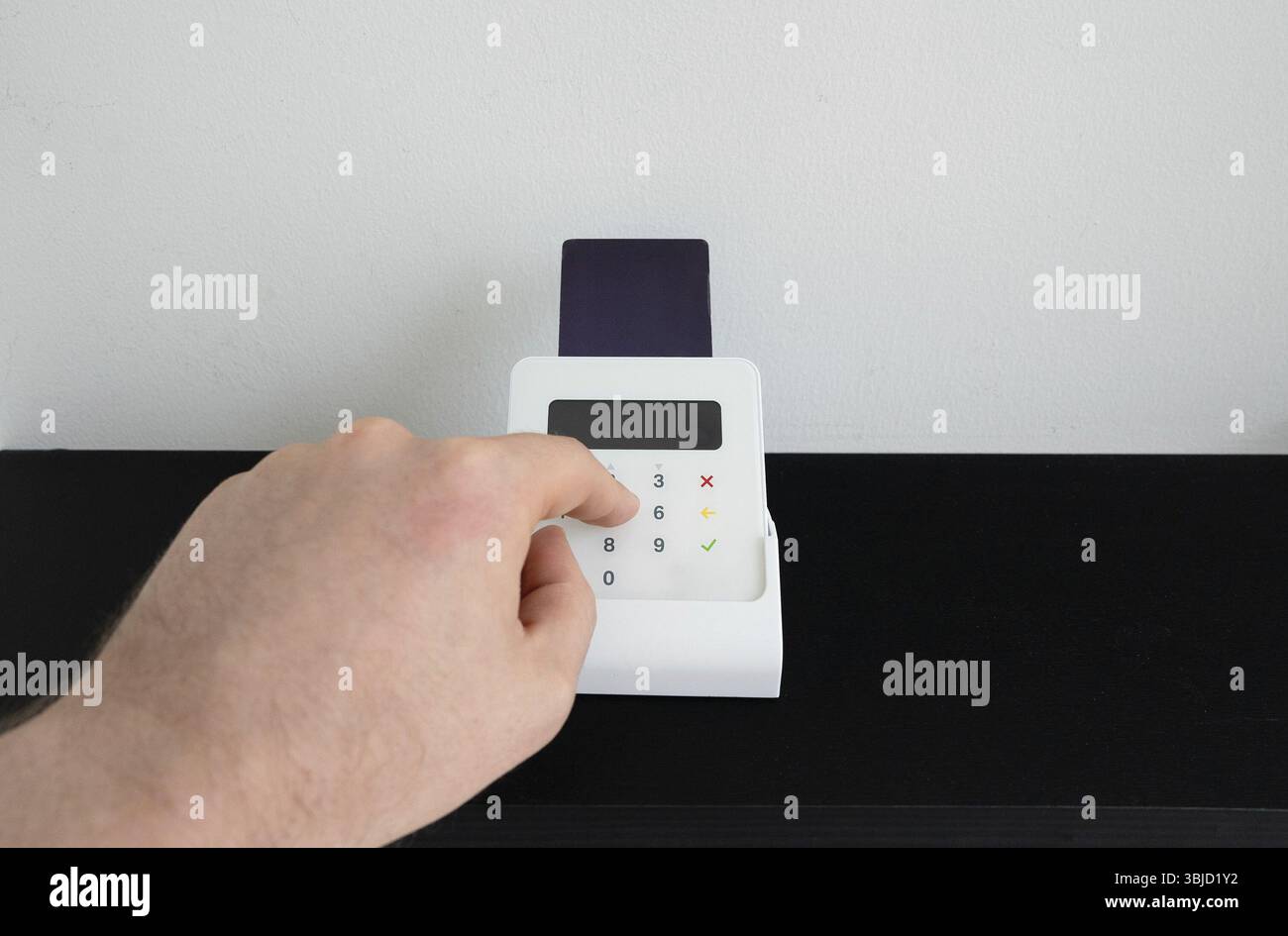 Die Hand des Mannes gibt einen PIN-Code an einem drahtlosen Zahlungsterminal ein Stockfoto