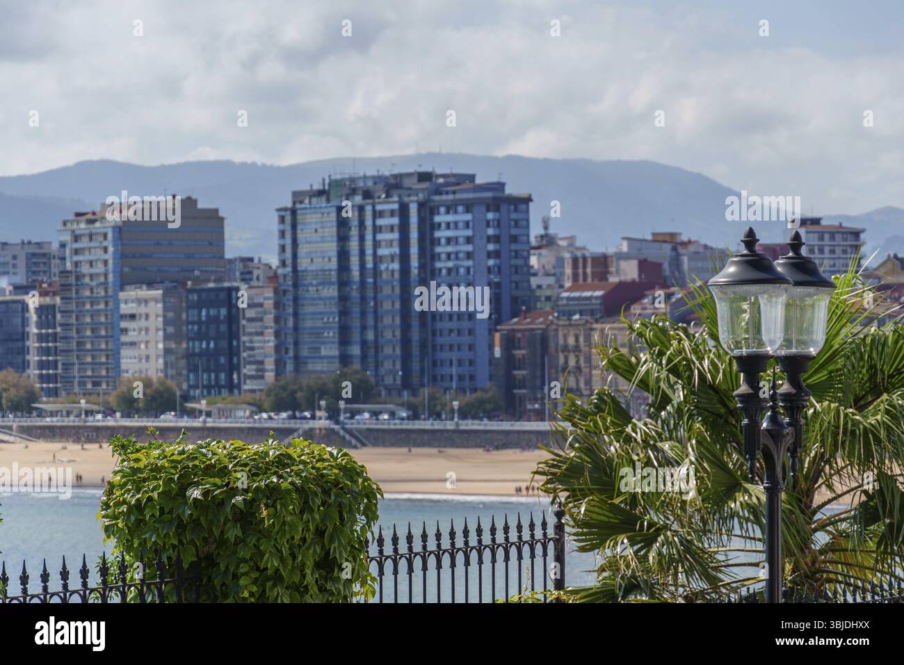Städtische Küste mit Wolkenkratzern, Bergen im Hintergrund und Lampen im Vordergrund, Gijon, Asturien, Spanien, Europa Stockfoto