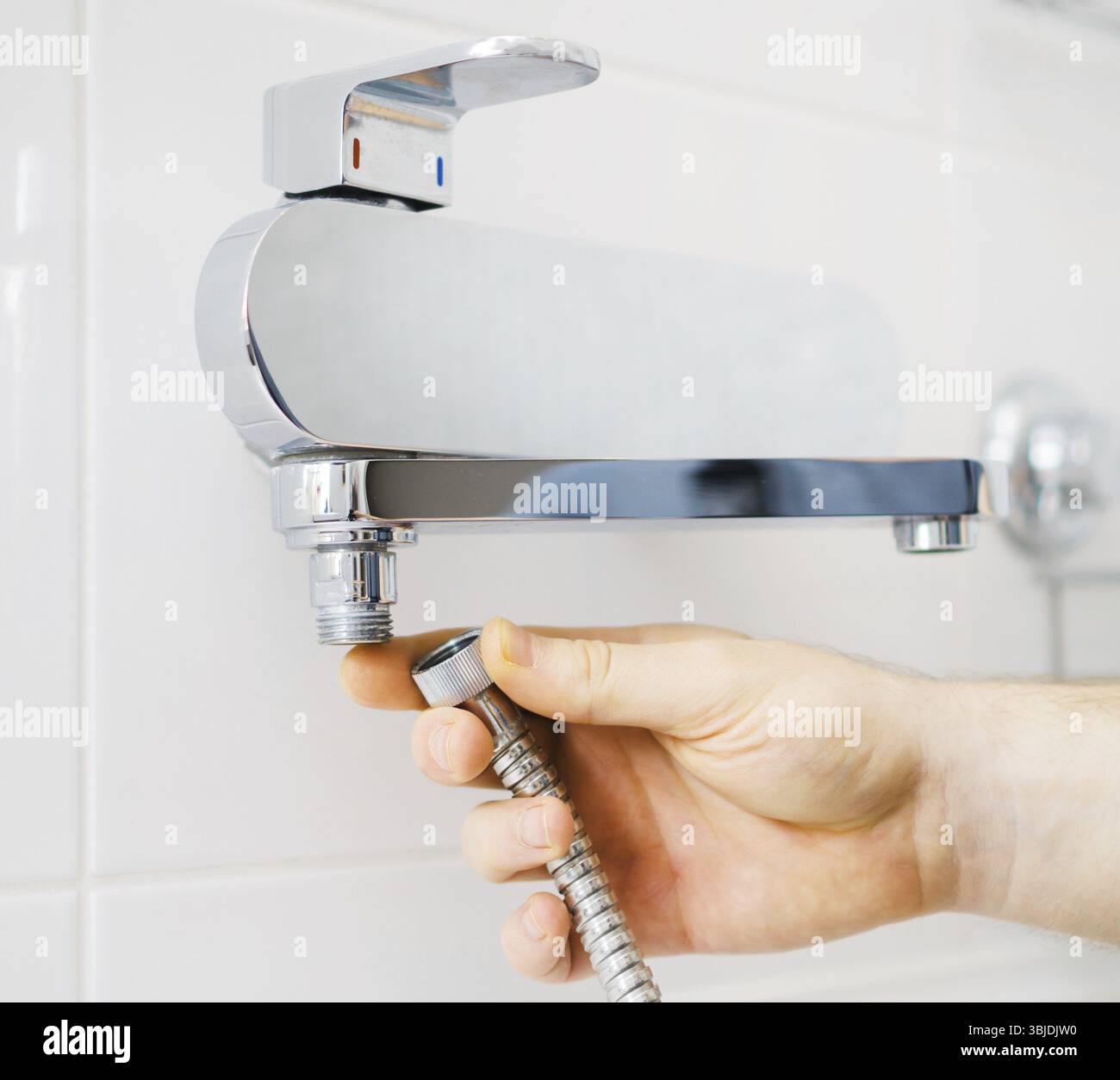 Klempnerhände befestigen den Duschmischer an einem modernen Wasserhahn Stockfoto