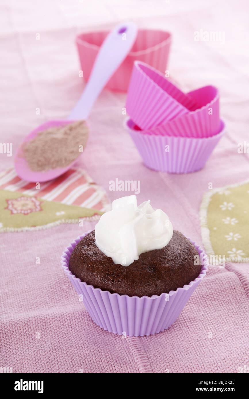 Moderner, zeitgenössischer Backhintergrund in lila und rosa. Schokoladen-Cupcake und Backformen mit Schlagsahne auf rosa Hintergrund Stockfoto Moderner, zeitgenössischer Backhintergrund in lila und rosa. Schokoladen-Cupcake und Backformen mit Schlagsahne auf rosa Hintergrund Stockfoto