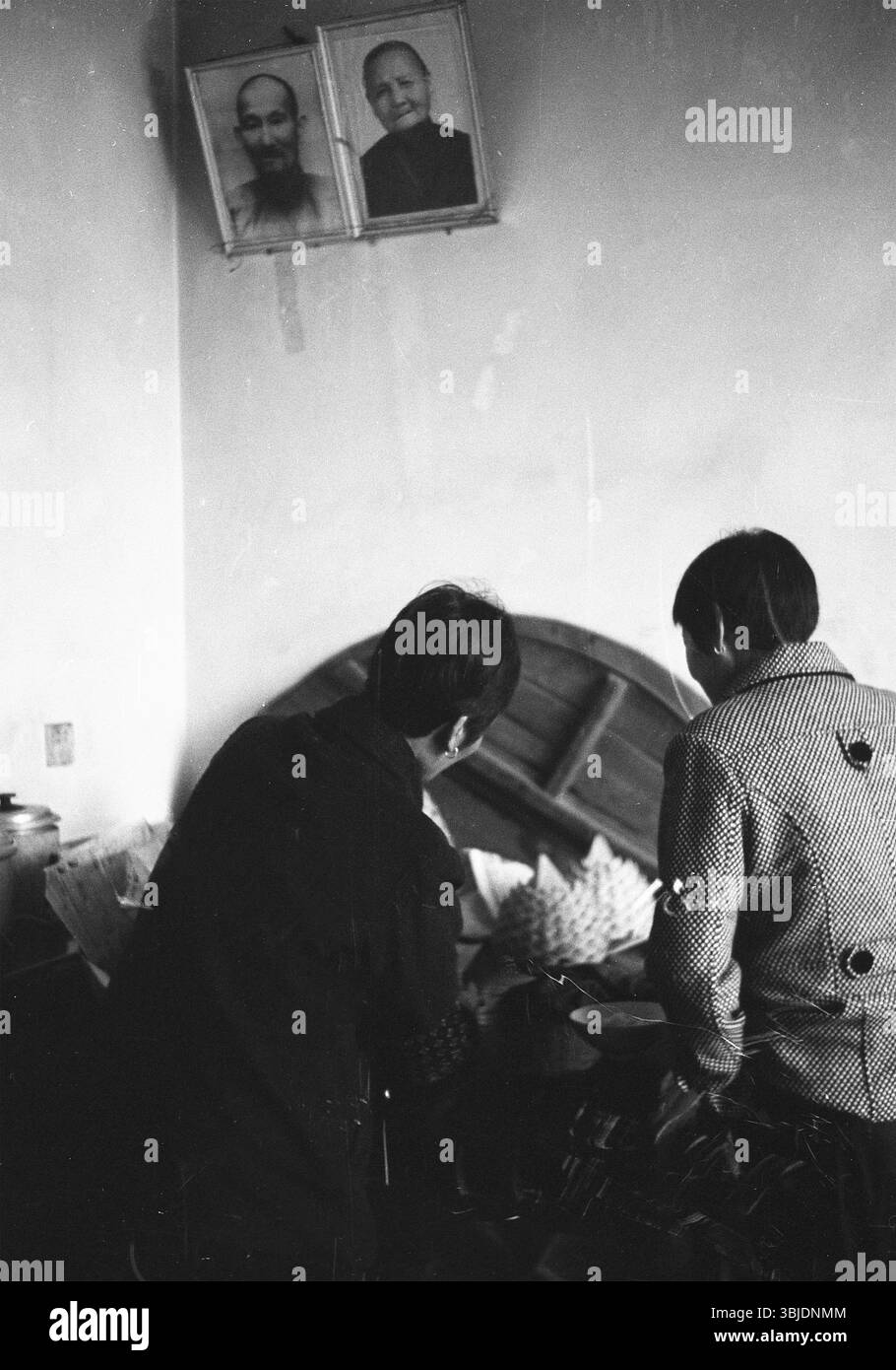 Ende der 2000er Jahre China ländlicher Vorfahren – ältere Ehepaare bereiten Opfer unter Familienporträts vor Stockfoto