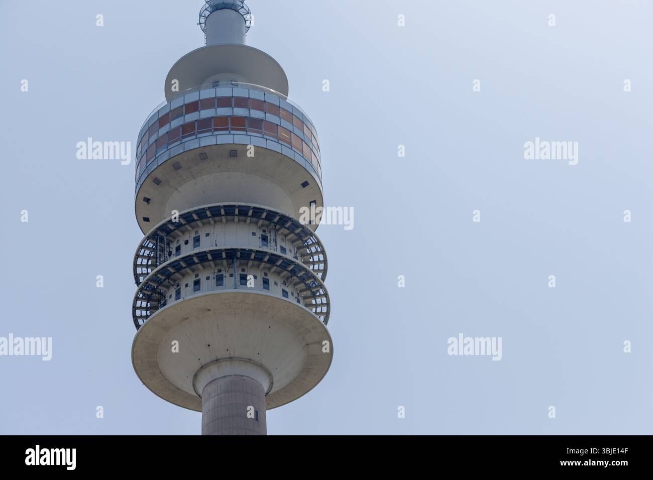 Eine Niedrigwinkelaufnahme eines Beton-Glas-Telekommunikationsturms vor einem hellblauen Himmel. Der Turm hat mehrere unterschiedliche Ebenen. Stockfoto