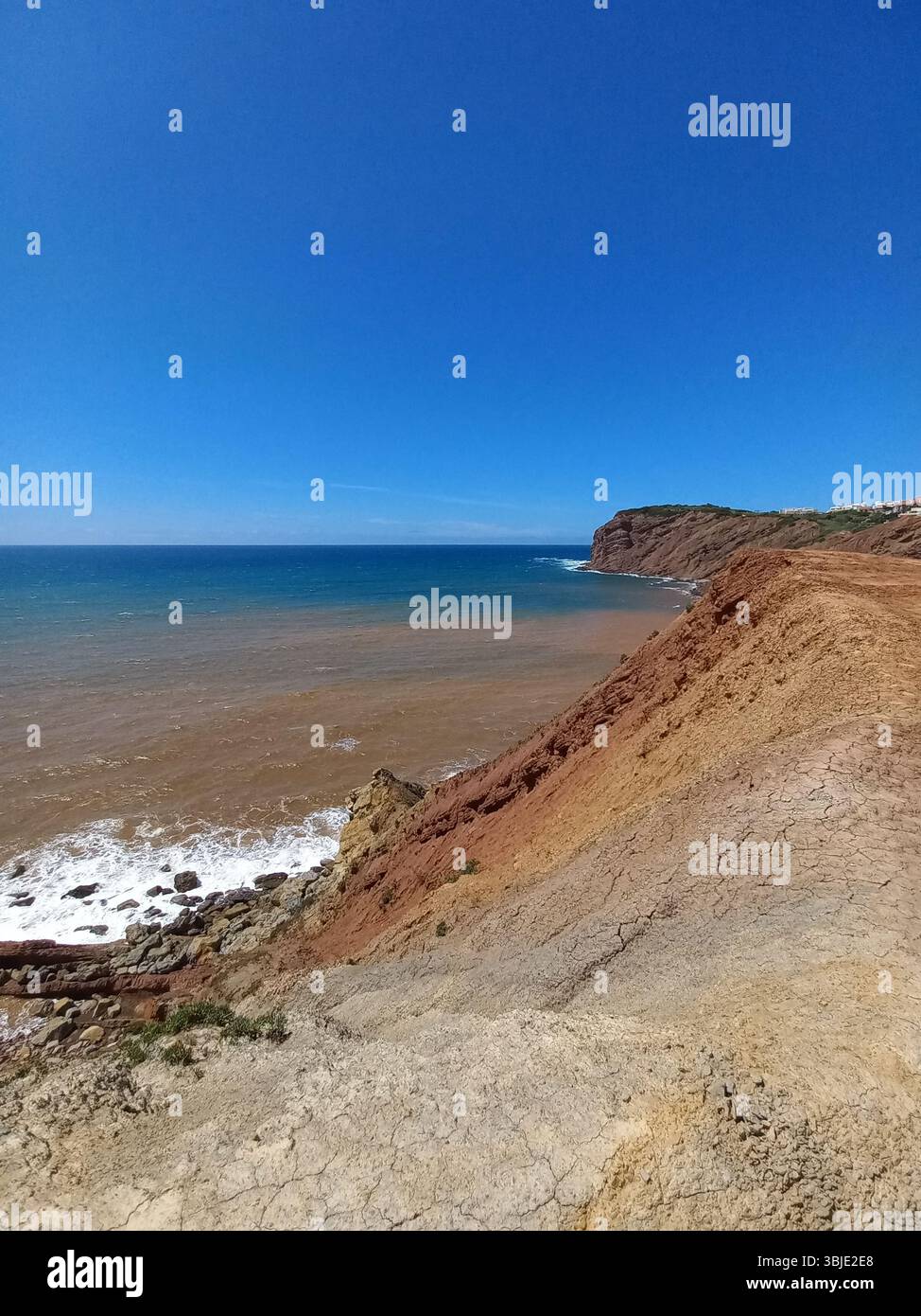 Zerklüftete Küste und felsige Klippen von São Martinho do Porto Portugal mit stürzenden Wellen und Panoramablick auf das Meer unter einem leuchtend blauen Himmel Stockfoto