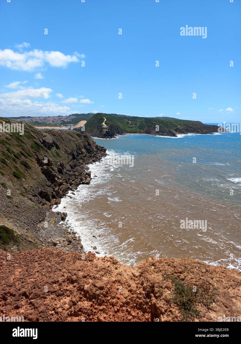 Zerklüftete Küste und felsige Klippen von São Martinho do Porto Portugal mit stürzenden Wellen und Panoramablick auf das Meer unter einem leuchtend blauen Himmel Stockfoto