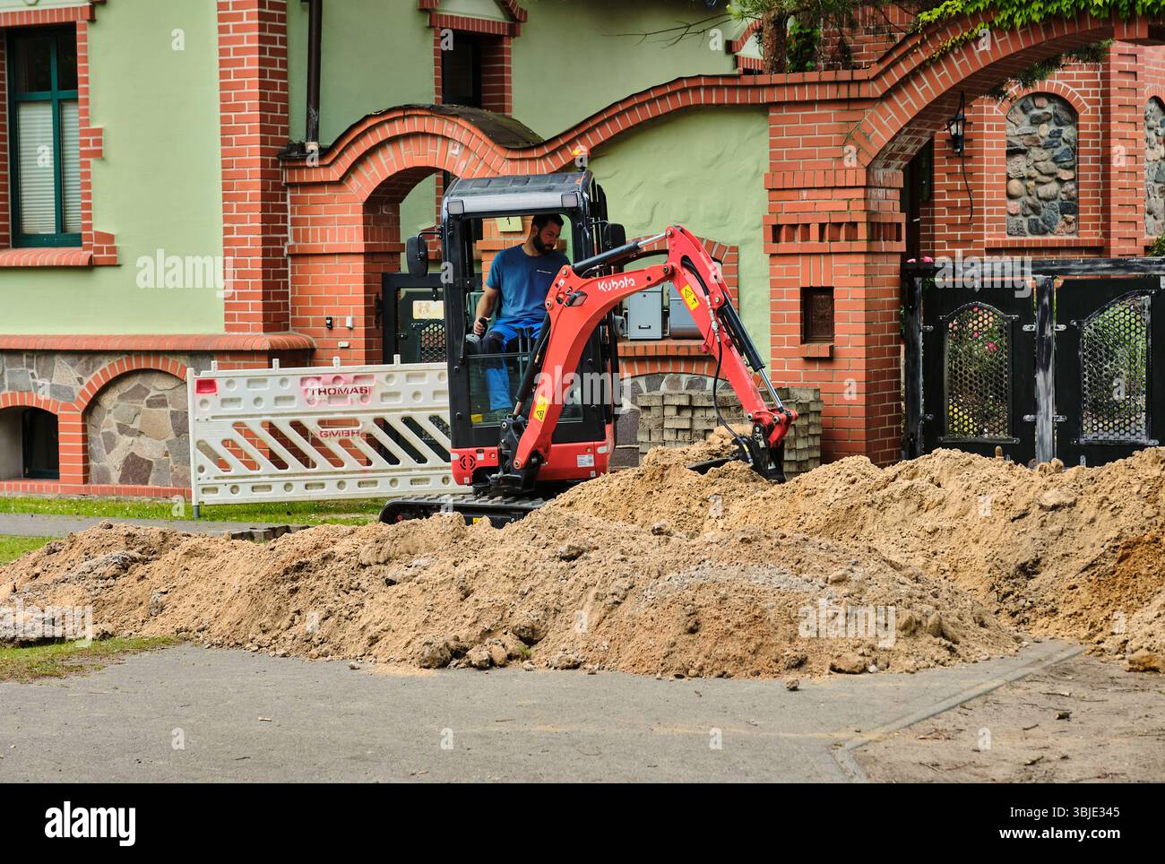 10. Juni 2025 – Teschendorf, Deutschland: Minibagger zur Vorbereitung des Grabens für die Glasfaserkabelinstallation, Teil der ländlichen deutschen Infrastrukturerweiterung Stockfoto