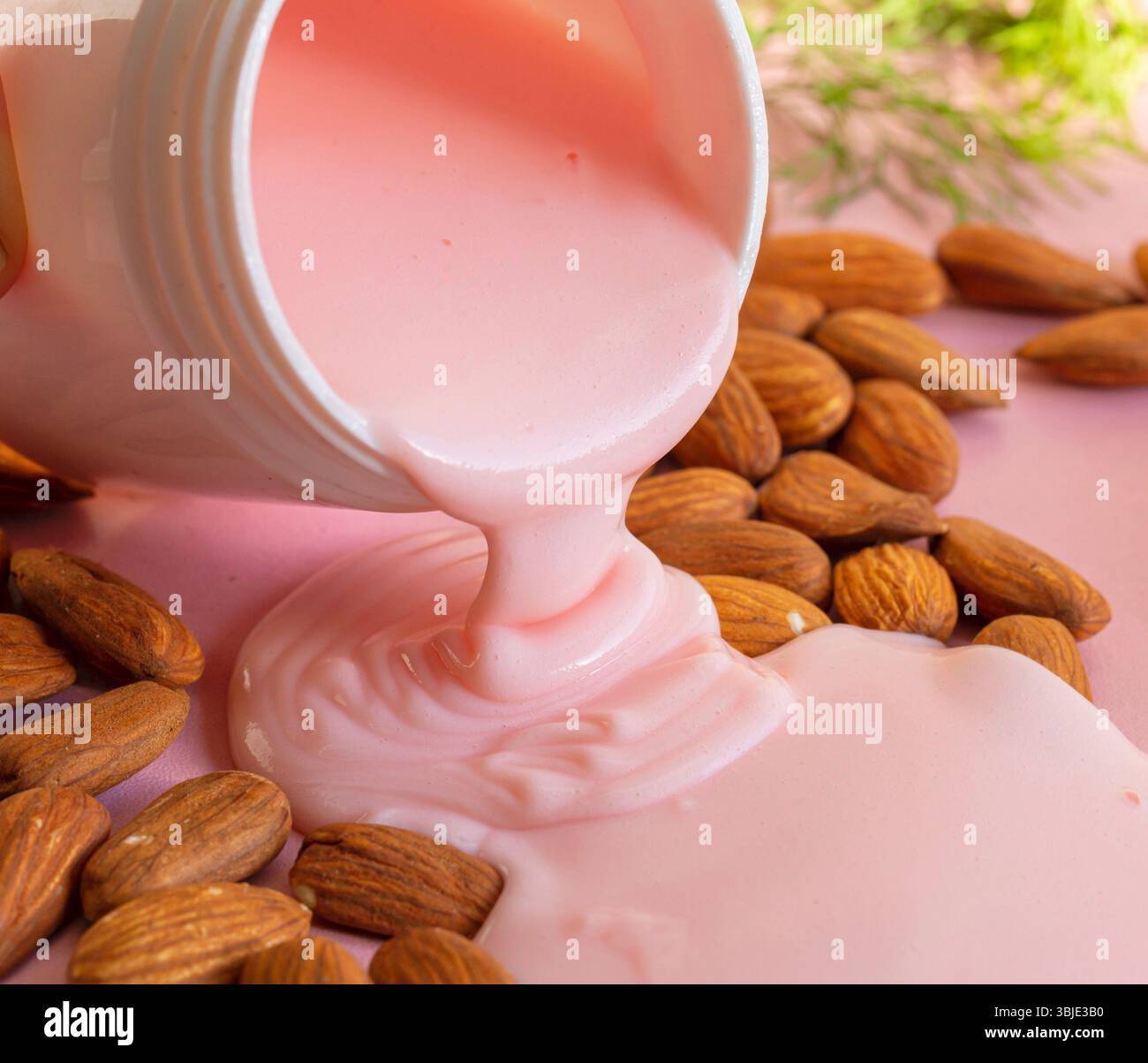 Hautpflegecreme auf Mandelölbasis, hochwertiges Gesichtsprodukt mit Mandelaroma und zartem Rosa. Stockfoto