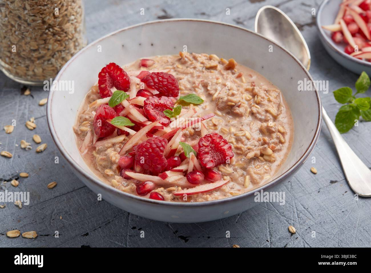 Haferflocken mit Apfel und Granatapfel – ein gesundes und farbenfrohes Frühstück in einer Schüssel, perfekt für die Zubereitung von Mahlzeiten und zum Frühstück. Stockfoto