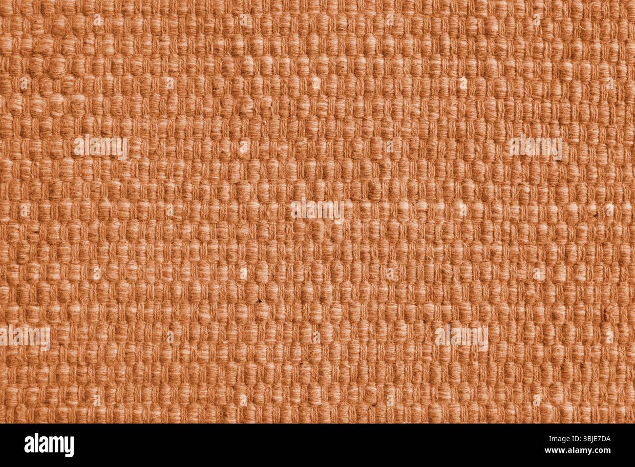 Textur aus orangefarbenem Naturstoff mit großer Webstruktur. Oberfläche, Struktur von Polstern oder Teppichmaterial, Stoffhintergrund aus der Nähe. Stockfoto