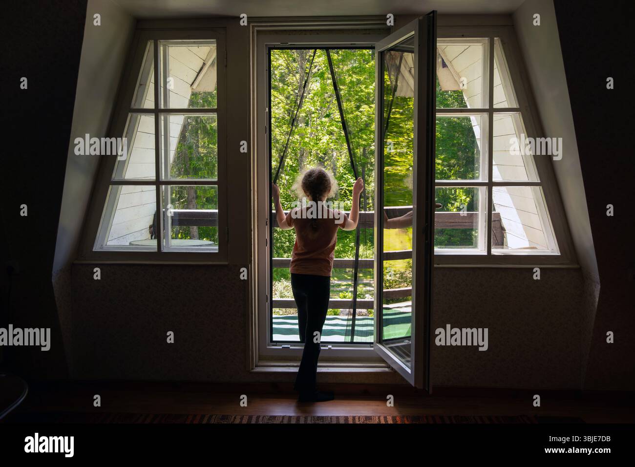Magnetisches Moskitonetz an der Balkontür. Kind geht nach draußen auf den Balkon und verhindert, dass Insekten ins Haus kommen. Stockfoto