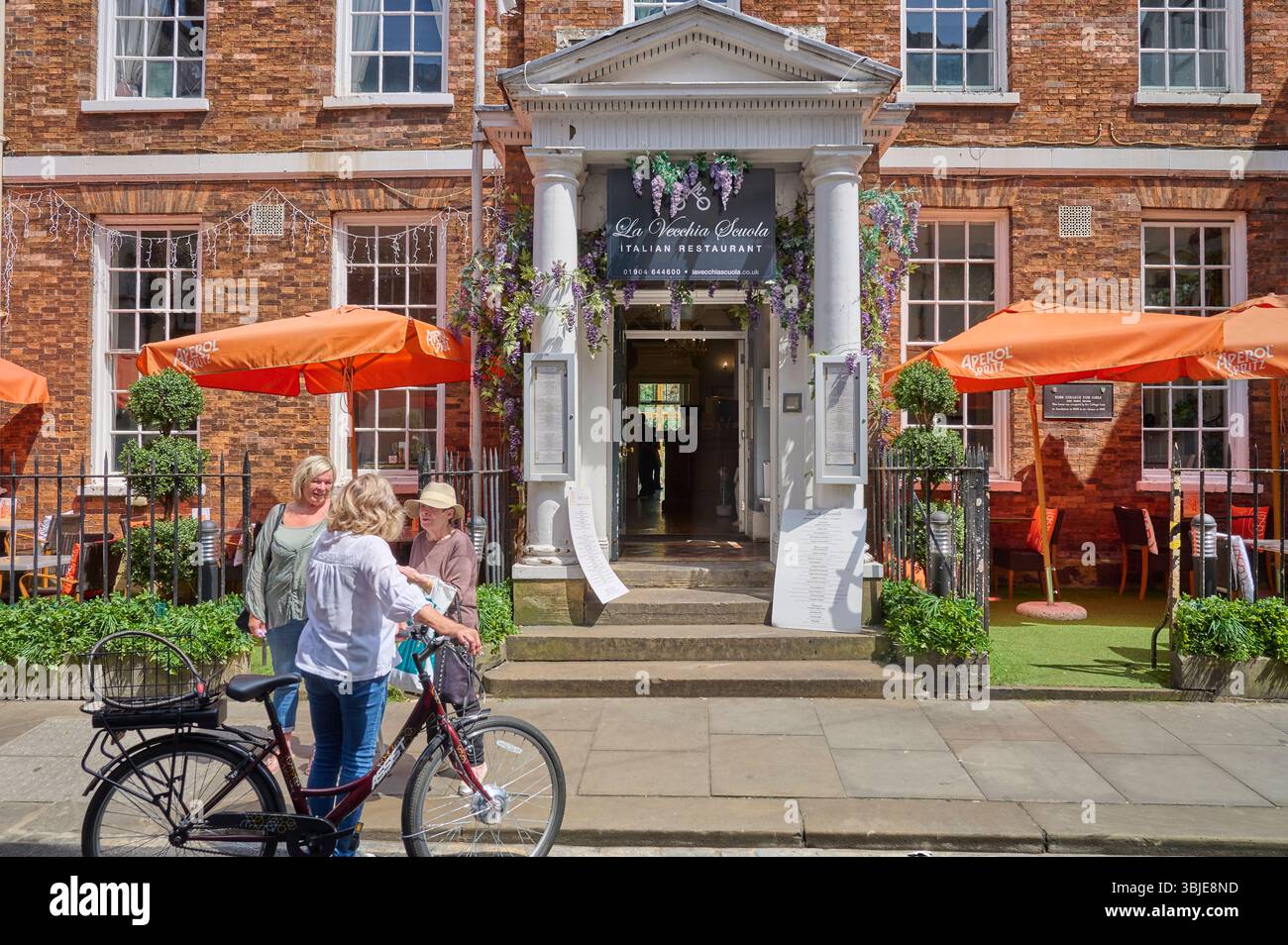 Gruppe von Frauen, die an einem sonnigen Sommertag vor dem italienischen Restaurant chatten, York, Großbritannien Stockfoto