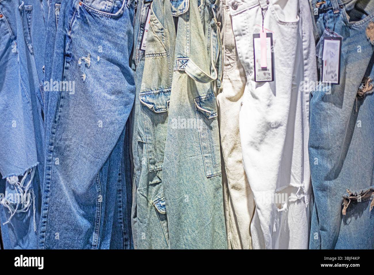 Stylische Jeans in verschiedenen Farben im Supermarkt. Saisonbeginn Stockfoto