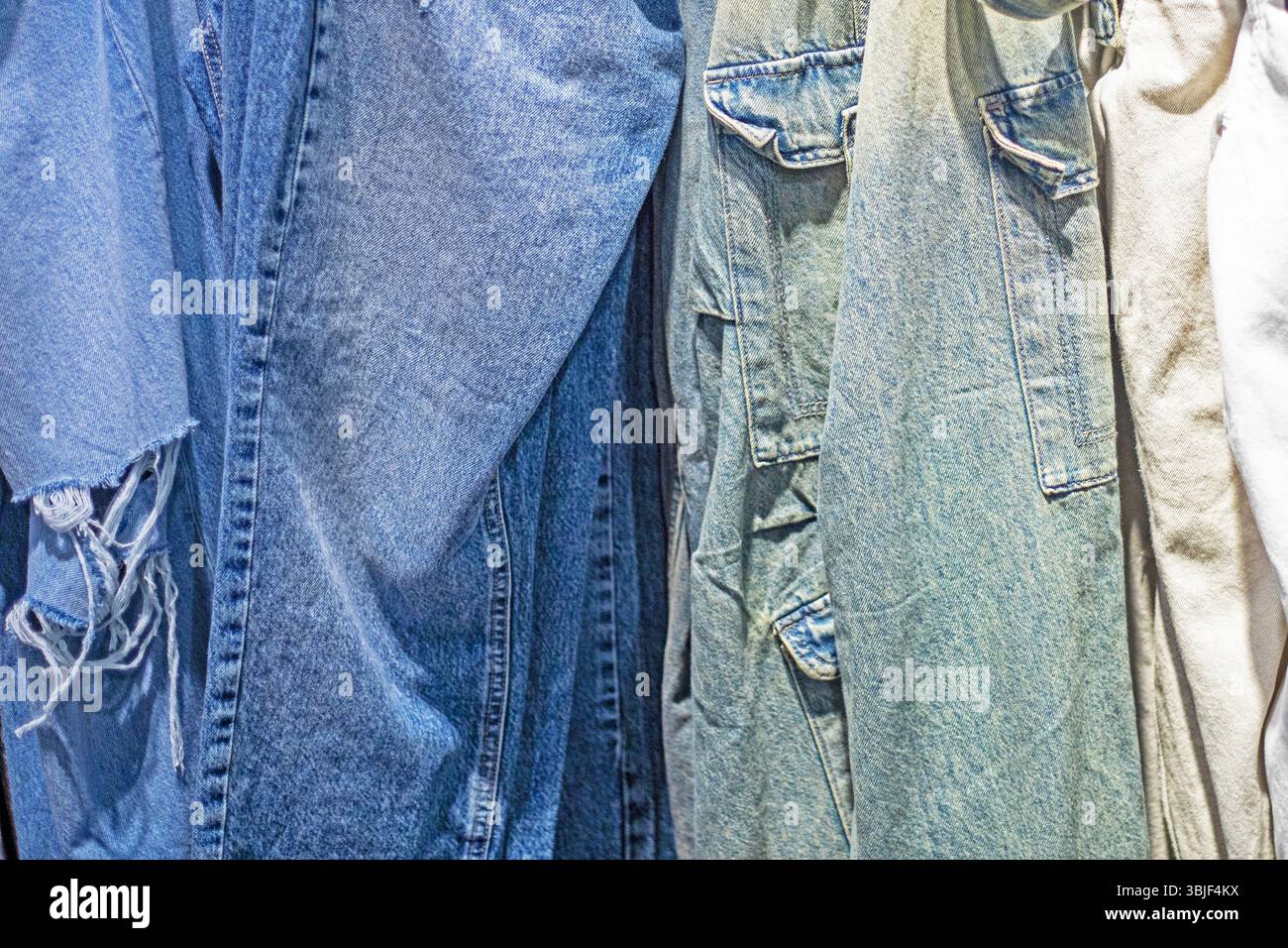 Stylische Jeans in verschiedenen Farben im Supermarkt. Saisonbeginn Stockfoto