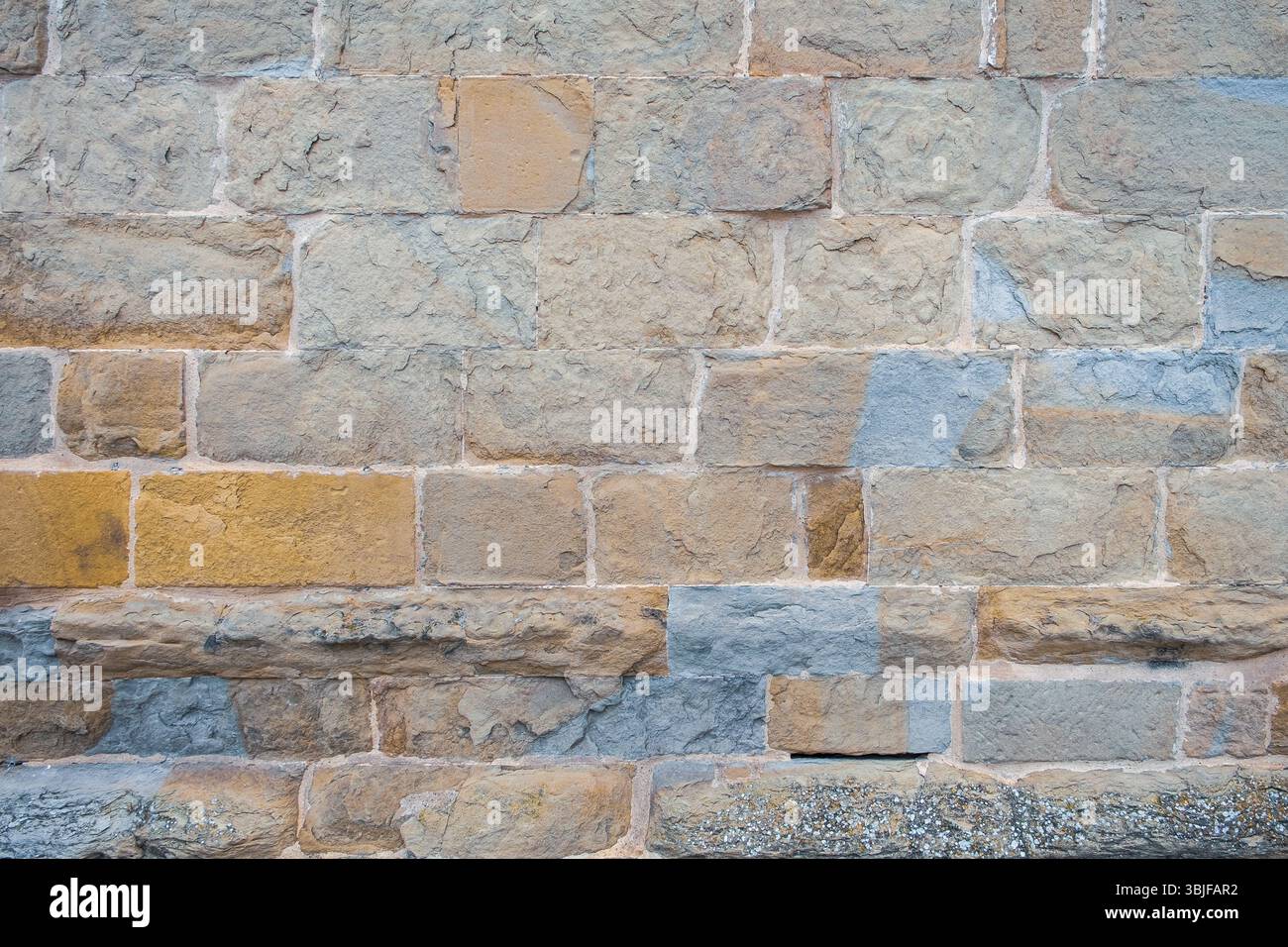 Alte Steinmauer mit viel Textur und Farbe. Abstraktes Muster einer alten roten, orangen und schwarzen Ziegelwand mit viel Textur, die für den Hintergrund nützlich ist Stockfoto
