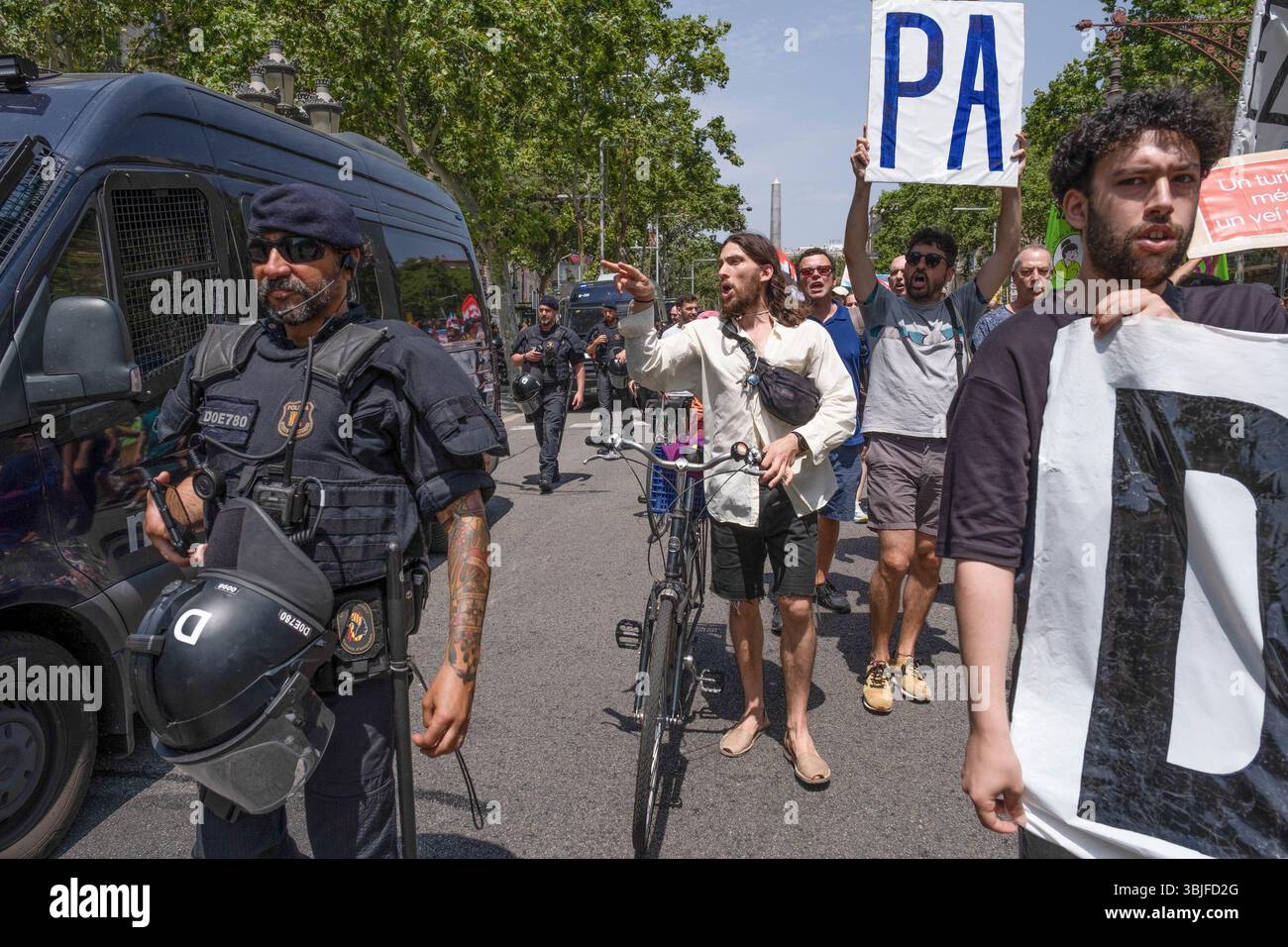 Barcelona, Spanien. Juni 2025. Während einer Demonstration gegen den Massentourismus rufen Demonstranten Slogans, während sie Banner und Plakate unter katalanischen Polizeibeamten tragen. Mehr als tausend Demonstranten marschierten durch das Zentrum Barcelonas zur Basilika Sagrada Família gegen die touristische Gestaltung Barcelonas, die prekäre Arbeitsplätze im Dienstleistungssektor schafft und die Immobilienpreise erhöht. Quelle: SOPA Images Limited/Alamy Live News Stockfoto