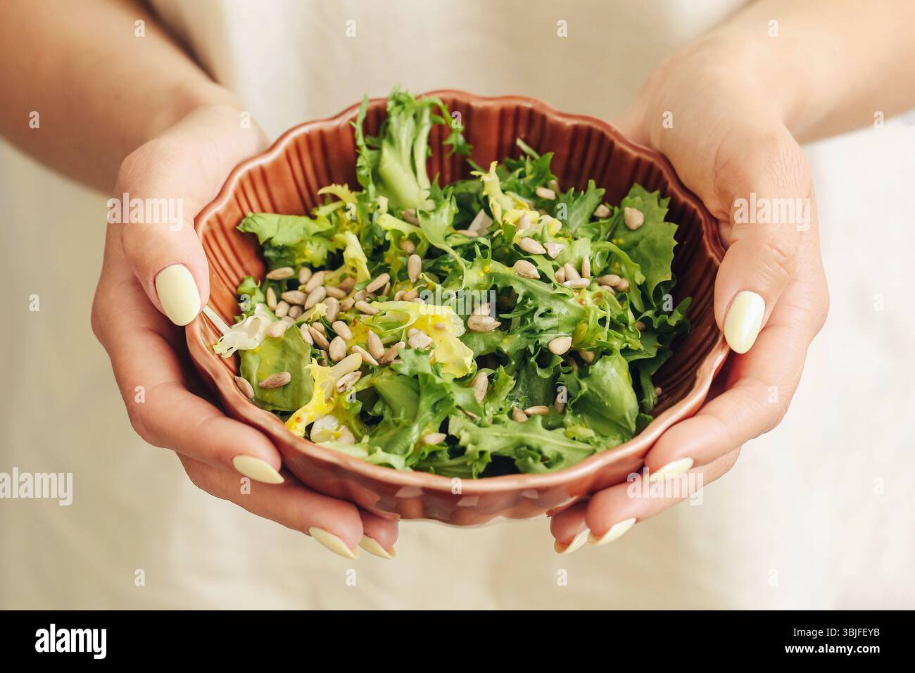 Salat in den Händen. Grüne Blätter Nahaufnahme. Veganer gesunder Lebensstil. Rustikale Keramikschale. Natürliche Ernährung. Sauberes Esskonzept. Wellness-Diät-Bild. Stockfoto