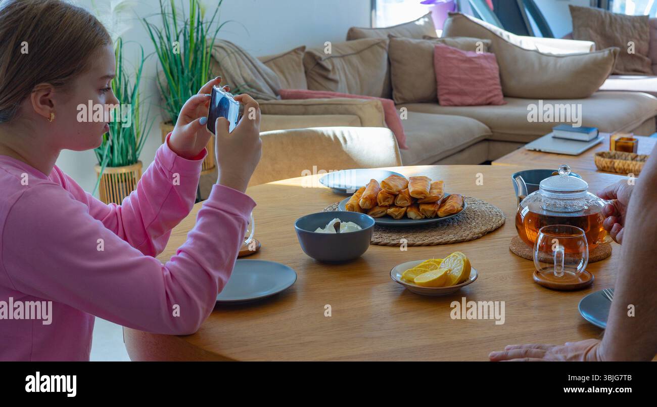 Entspannter Tee-Moment mit Teekanne und Smartphone auf Holztisch. Helles Tageslicht und gemütliche Atmosphäre im modernen Wohnzimmer Stockfoto
