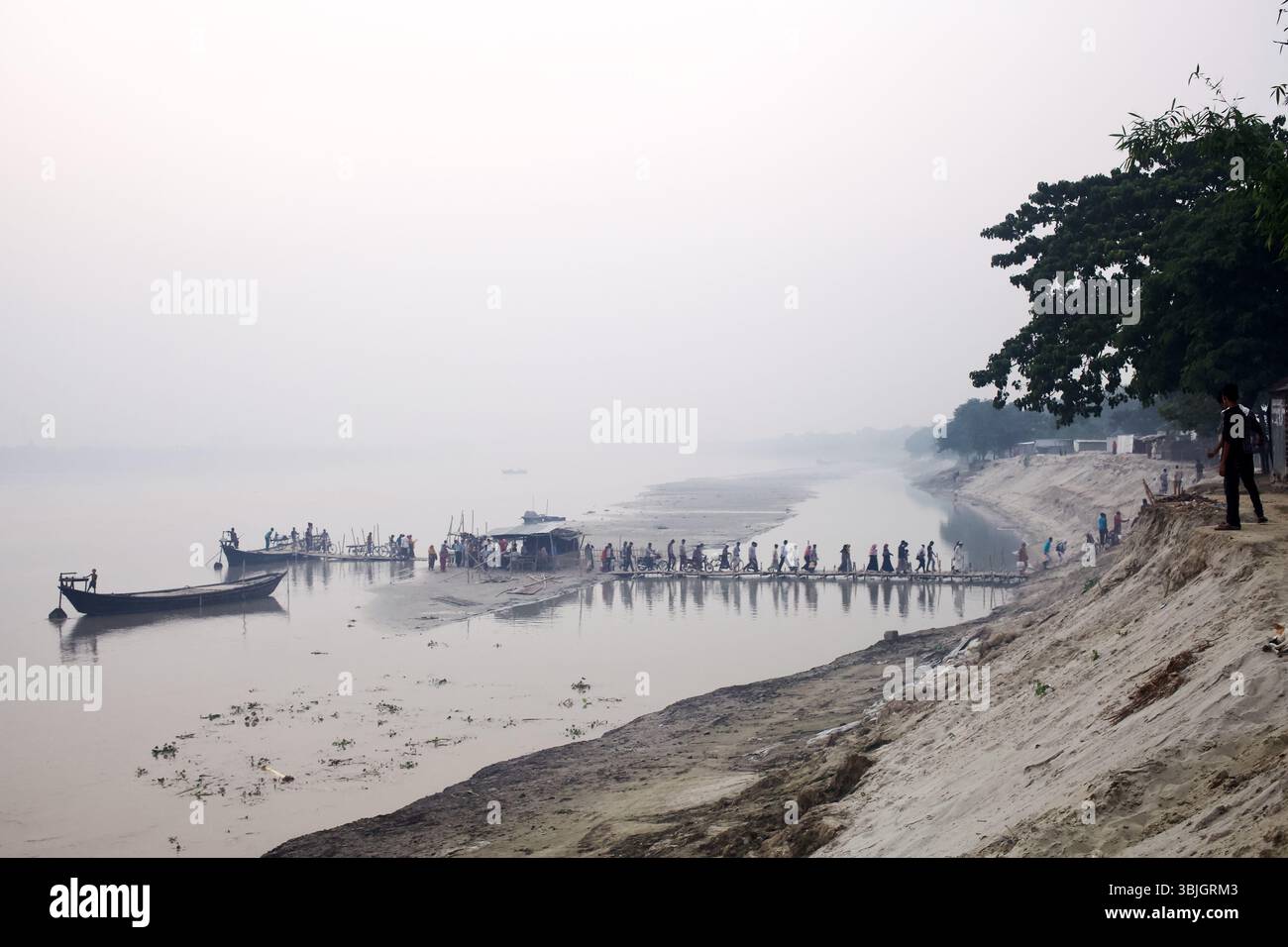 Passagiere überqueren eine Bambus-Fußgängerbrücke zu Flussbooten auf dem Madhumati-Fluss, die Kushtia mit der Gattia-Kuthibari-Straße im ländlichen Bangladesch verbinden. Stockfoto