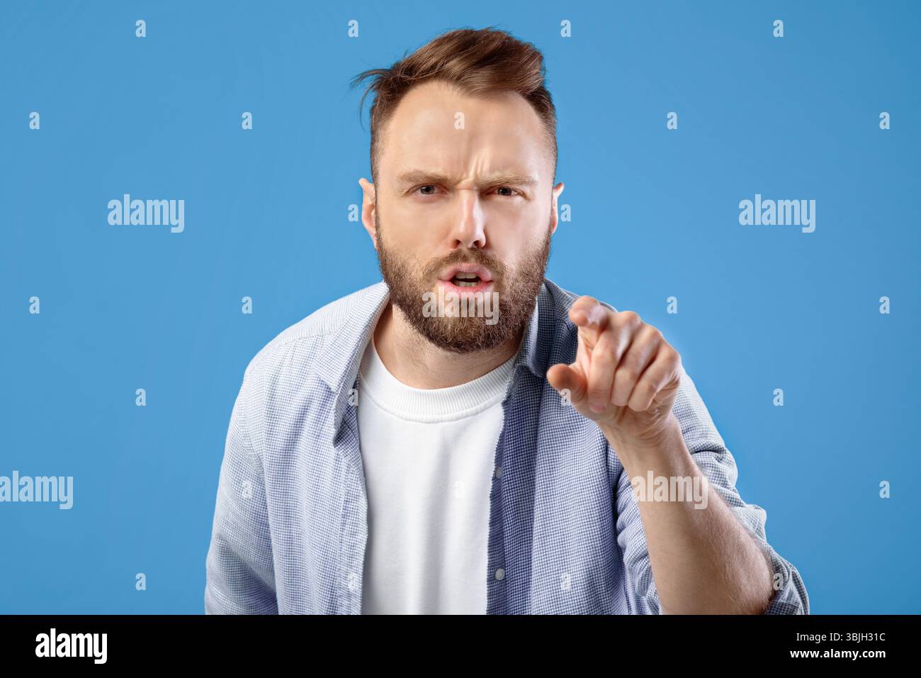Es ist Ihre Schuld. Wütender kaukasischer Mann, der mit dem Finger auf den Bildschirm zeigt, in Anschuldigung auf blauem Studiohintergrund Stockfoto