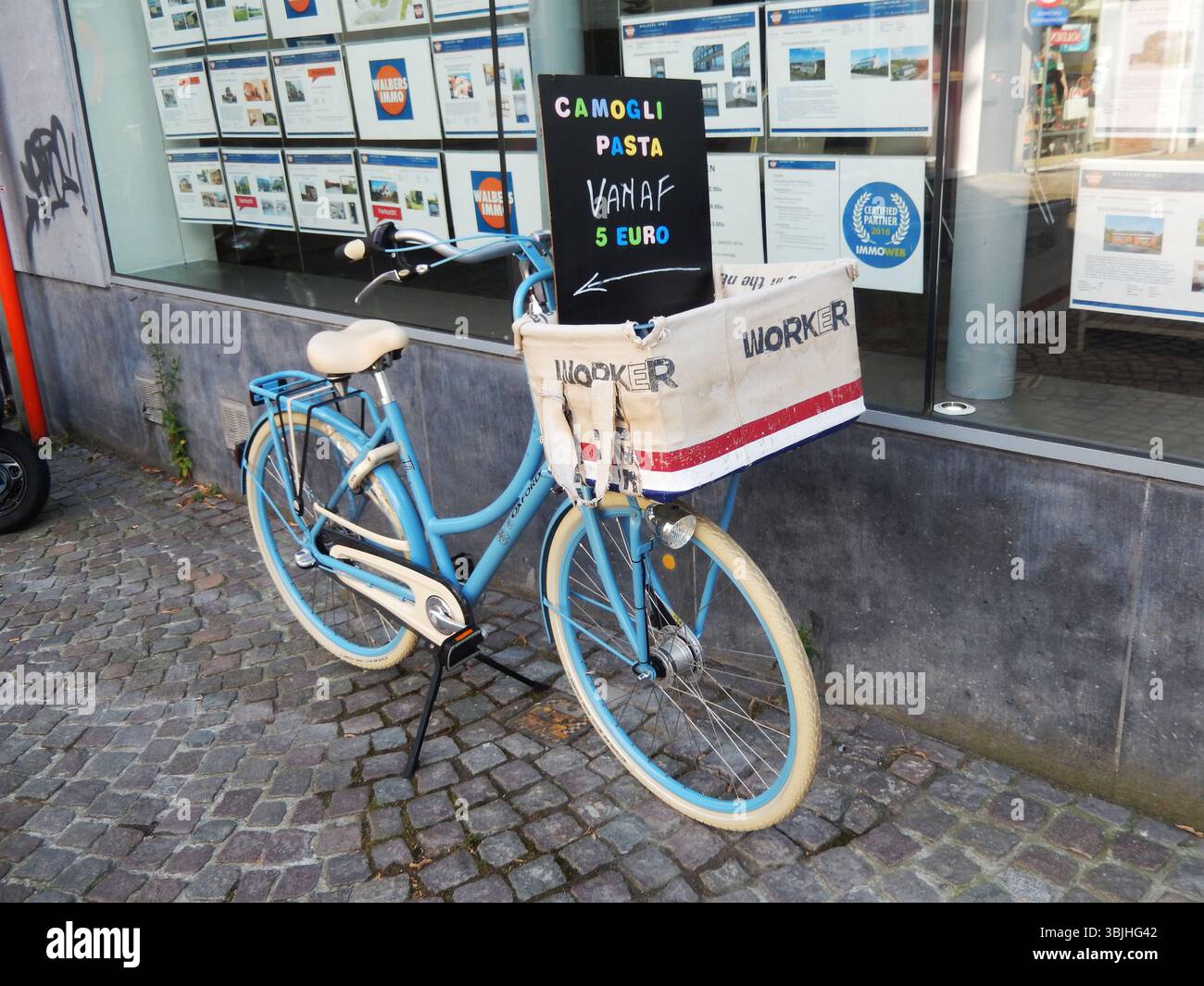 Blaues Vintage-Fahrrad mit Korb mit Pasta-Werbung. Mechelen, Belgien Stockfoto