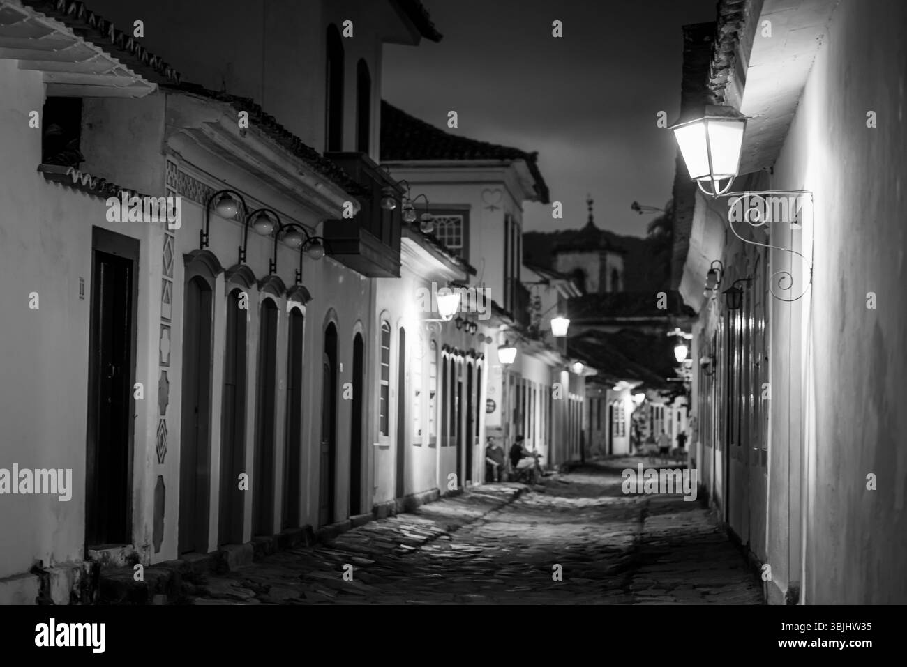 Schwarz-weiß-Blick auf die historische Gasse, beleuchtet von Straßenlaternen in Paraty, Brasilien Stockfoto
