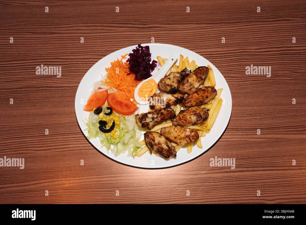 Türkischer Kebab-Teller mit Pommes, Gemüse und Huhn. Köstliche frisch zubereitete Mahlzeit, perfekt für Menüs, Restaurants oder Konzepte zur Lieferung von Speisen. Stockfoto
