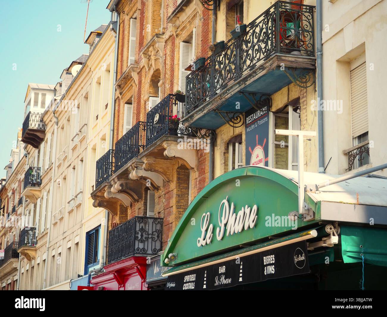 Bezaubernde Straßenszene in der Normandie mit französischen Balkonen und traditionellem Café Stockfoto
