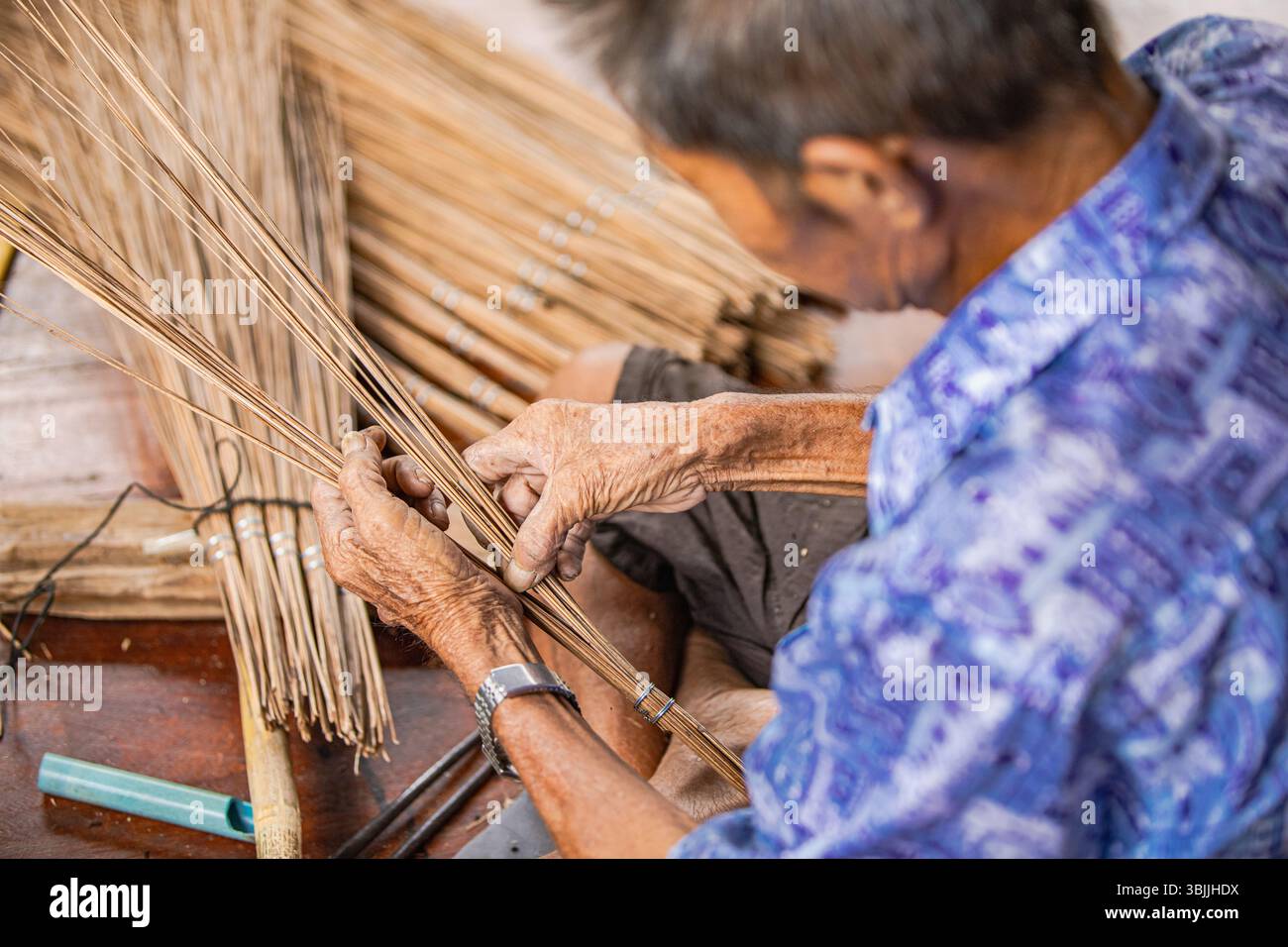 Über Schulter thailändischer Handwerker, der Kokosnussbesen webt Stockfoto