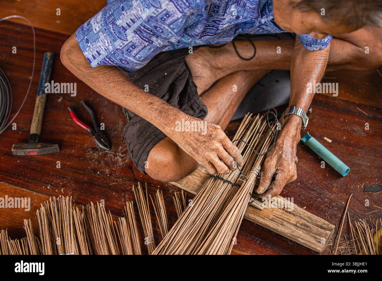 Ein thailändischer Handwerker bündelt Kokosbesenfasern fest zusammen Stockfoto