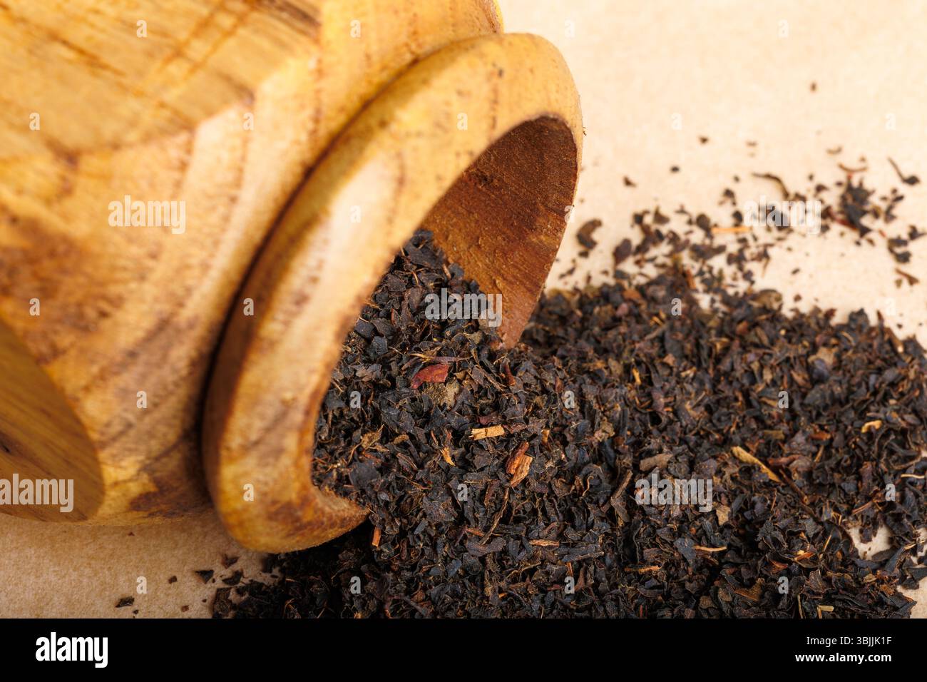 Trockene schwarze Teeblätter in Holzmörtel Stockfoto