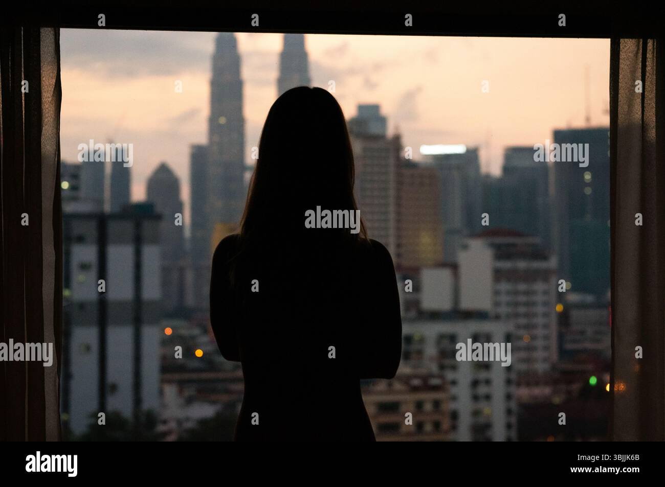 Silhouette einer Frau bei Sonnenuntergang mit Skyline der Stadt Stockfoto