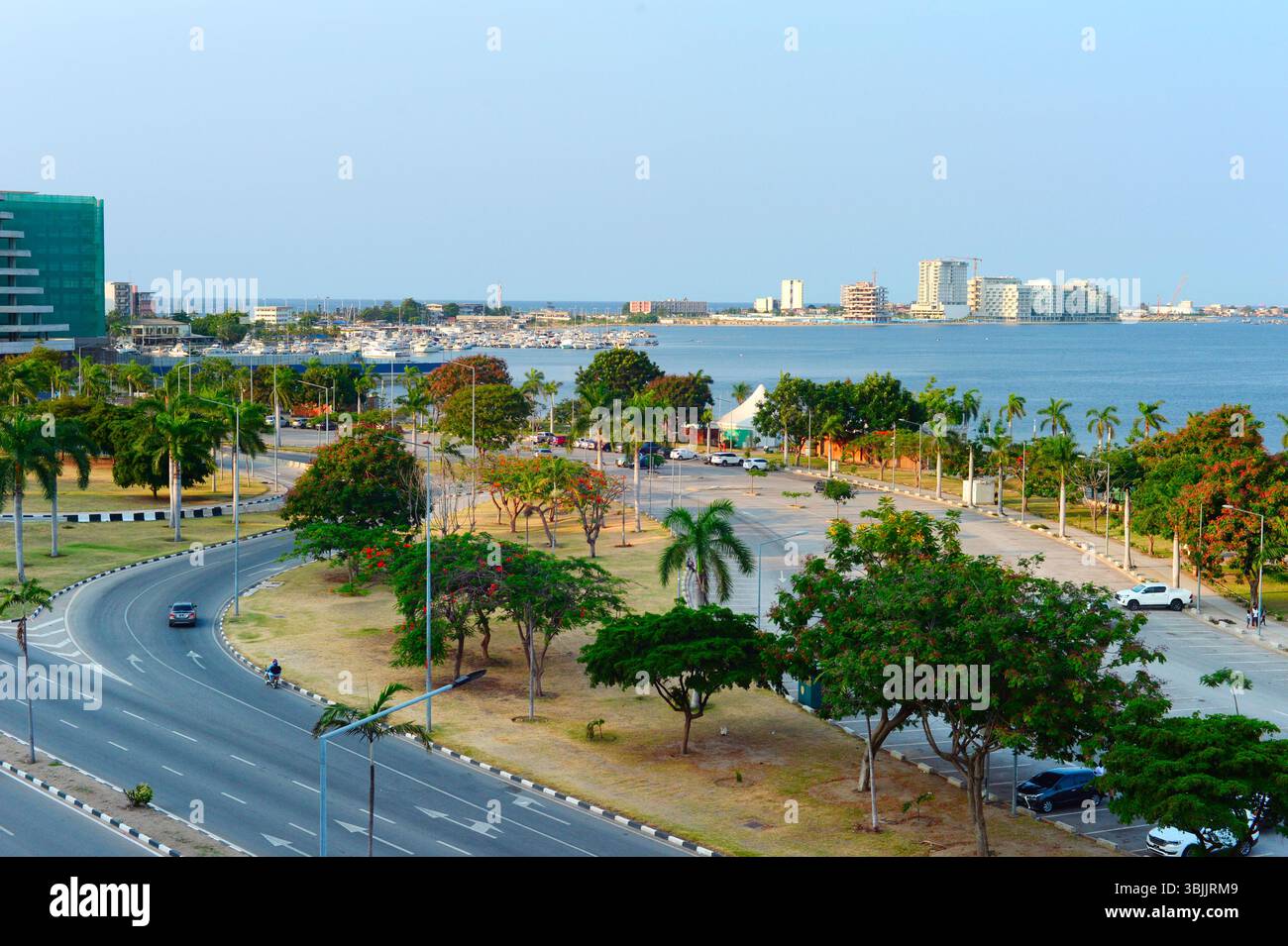 Blick auf eine Straße, Yachtclub und Ilha de Luanda bei Sonnenuntergang. Luanda, Angola Stockfoto