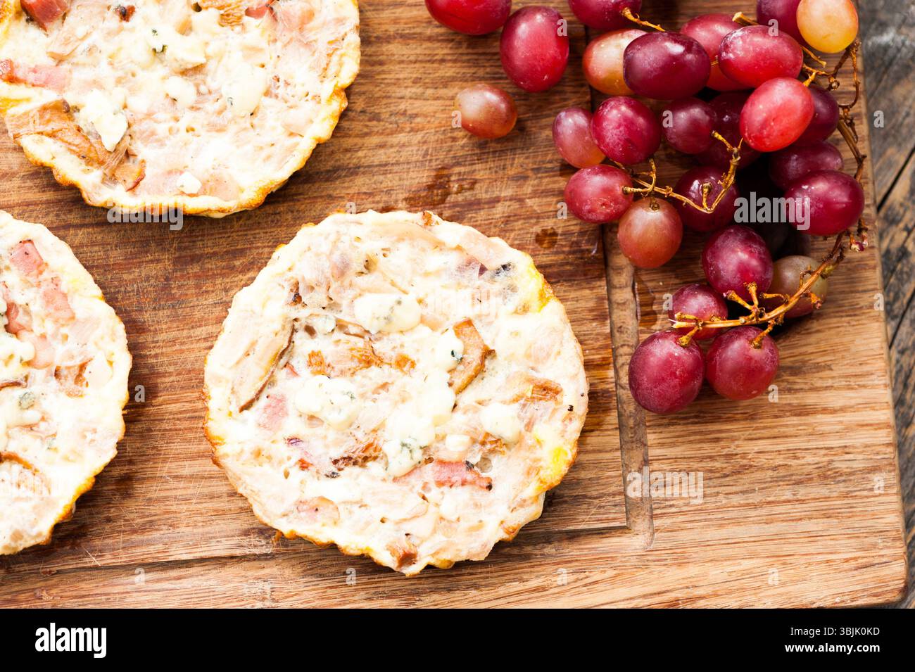 Mini-Quiche auf hölzernem Hintergrund mit Trauben Stockfoto