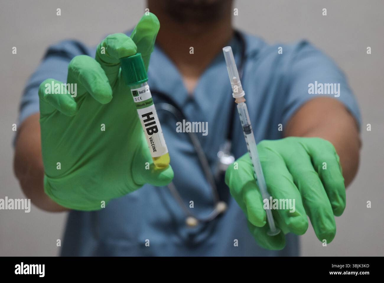 Text Hib Vaccine of ist auf einer Flasche mit Hintergrund eines Arztes mit einer Spritze in einer medizinischen Handschuhmaske geschrieben. Medizinisches Konzept Stockfoto